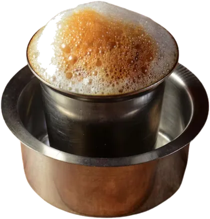 South Indian filter coffee frothing over a steel tumbler set in its dabara