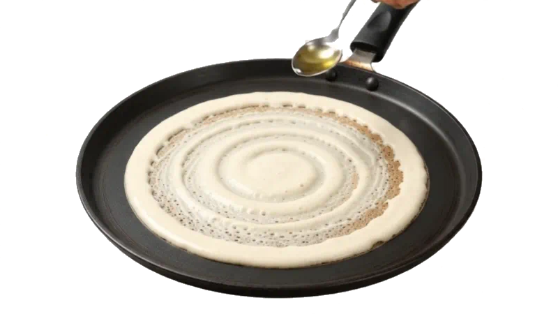 A dosa being made on the tawa: batter poured and spread thin, then the masala filling